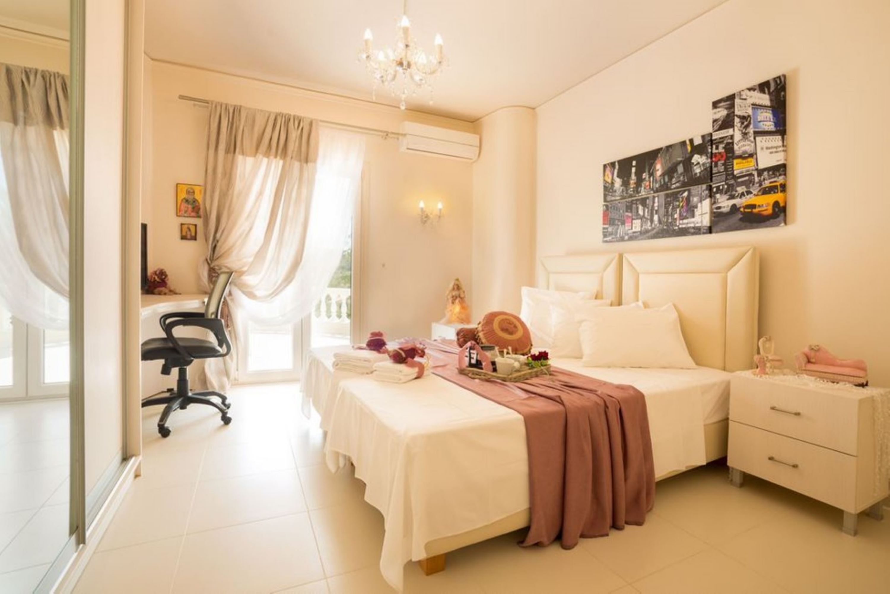 Ein Hotelzimmer mit Bett, Schreibtisch, Stuhl, Nachttisch und einem Wandbild mit Stadtansicht.