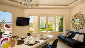 Un coin repas avec une table mise pour le petit-déjeuner, un canapé et un téléviseur fixé au mur.