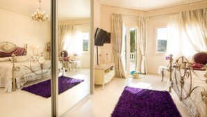 Une chambre spacieuse dotée d’un grand miroir, d’un lit avec une tête de lit en métal décorée, d’une télévision et d’un balcon agrémenté de rideaux.