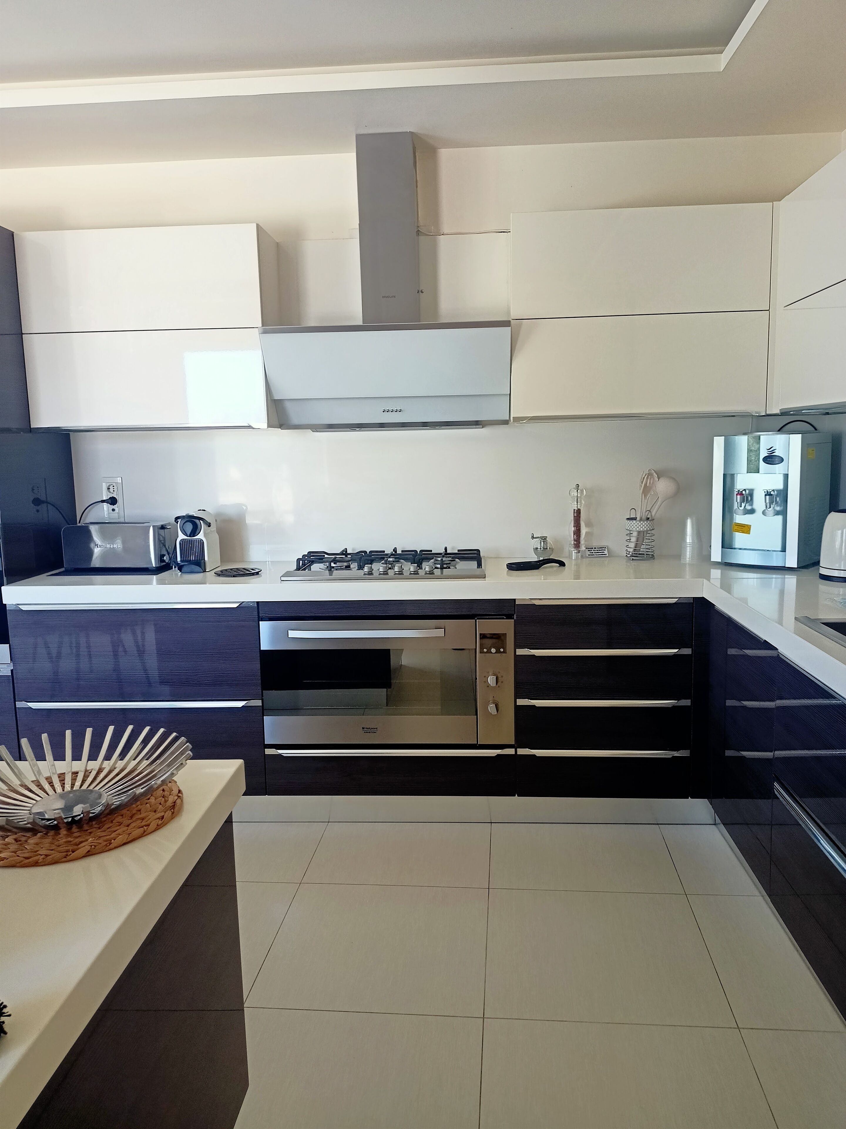 A modern kitchen with a built-in oven, a water dispenser, and a stove.