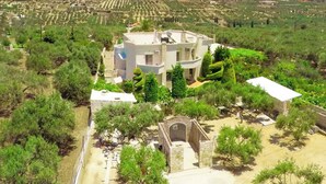 Une villa moderne dotée d’une cour intérieure, entourée d’une végétation luxuriante et, au loin, de champs en terrasses.
