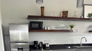 A modern kitchen with a glass dining table, chairs, and a potted plant.