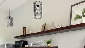 A modern kitchen with grey cabinets, a black countertop, stainless steel appliances, and hanging pendant lights.