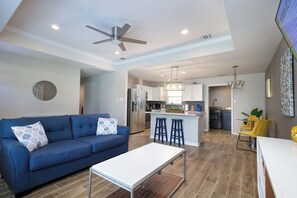 A modern living room with a blue sofa, a white coffee table, and a ceiling fan. - 3BR Near Lackland AFB • Military & ALE Stays • W/D (San Antonio)