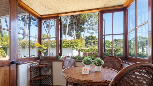 A sunroom with a large window, wicker furniture, and a sign reading "GT HOUSE".