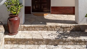 A stone staircase leading to a dark wooden door with a small potted plant beside it.