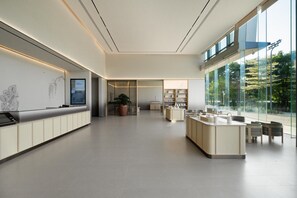 A modern hotel lobby with a reception desk, seating area, and large windows offering a view of the outdoors. - Ji Hotel Guangzhou Huangpu Science City Luogang (Guangzhou)