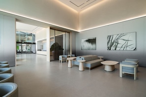A modern lobby with a sofa, round tables, and a glass door leading to a balcony. - Ji Hotel Guangzhou Huangpu Science City Luogang (Guangzhou)