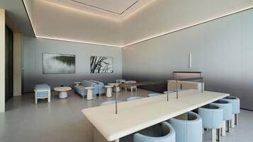 A modern, minimalist lounge area with a long table, several seating options, and abstract wall art.