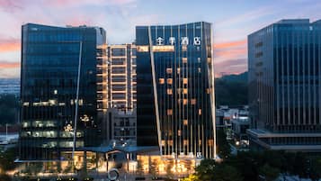 A modern hotel with a prominent glass facade and illuminated signage.