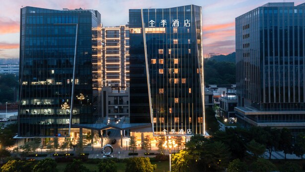 A modern hotel with a prominent glass facade and illuminated signage. - Ji Hotel Guangzhou Huangpu Science City Luogang (Guangzhou)