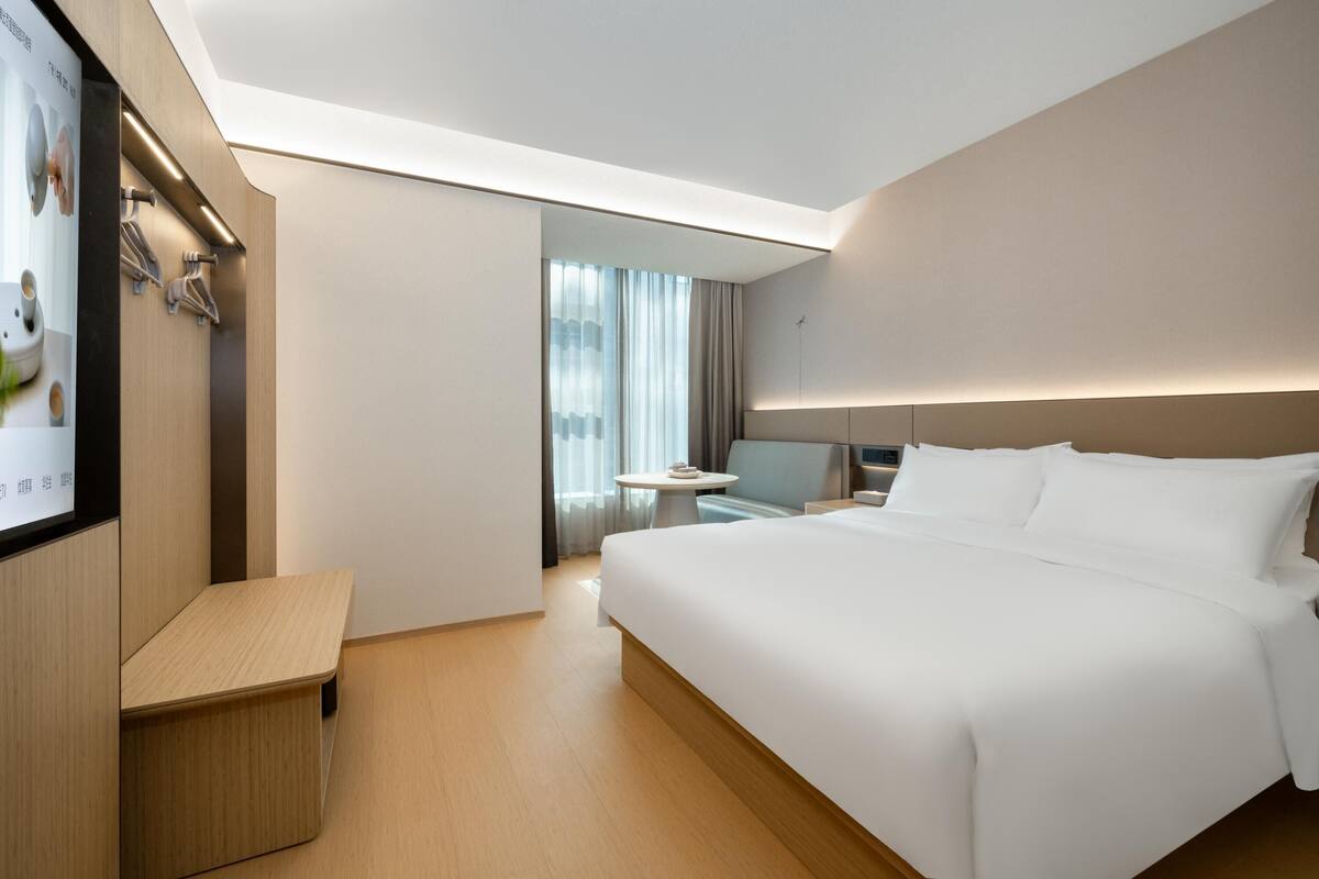 Ein modernes Hotelzimmer mit einem großen Bett, einem Schreibtisch und einem Fernseher.