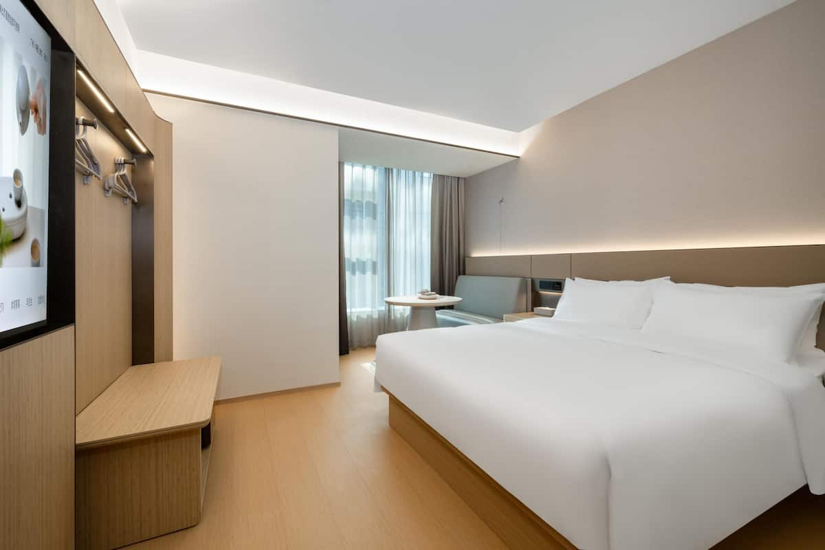A modern hotel room with a large bed, a desk, and a television.