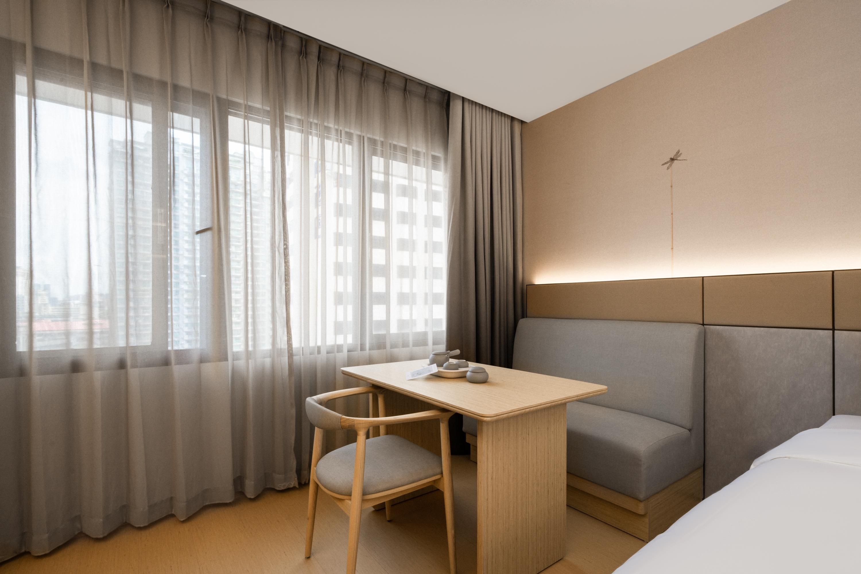 Una habitación de hotel con cama, escritorio, silla y sofá.