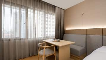 A hotel room with a bed, a desk, a chair, and a sofa.