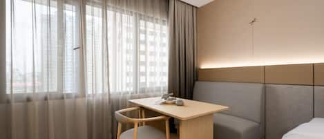 Una habitación de hotel con cama, escritorio, silla y sofá.