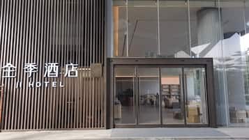 A hotel entrance with a modern design, featuring a vertical wooden panel and a glass door entrance.