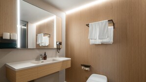 A modern bathroom with a wooden vanity, a mirror, a toilet, and a towel rack. - Ji Hotel Guangzhou Huangpu Science City Luogang (Guangzhou)