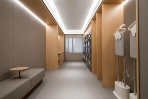 A modern laundry facility with a bench, washing machines, and a ceiling light. - Ji Hotel Guangzhou Huangpu Science City Luogang (Guangzhou)