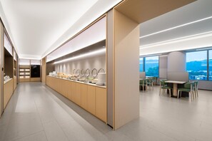 A modern, well-lit kitchen area with a long counter, various kitchenware, and a seating area with tables and chairs. - Ji Hotel Guangzhou Huangpu Science City Luogang (Guangzhou)