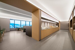 A modern kitchen with a long counter, built-in cabinets, and a view of the city. - Ji Hotel Guangzhou Huangpu Science City Luogang (Guangzhou)