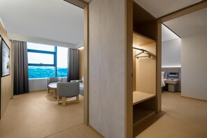 A modern hotel room with a large window, a seating area with two chairs, a wooden wardrobe, and a small bathroom. - Ji Hotel Guangzhou Huangpu Science City Luogang (Guangzhou)