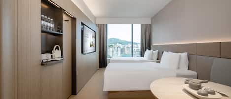 Una habitación de hotel moderna con una cama grande, una mesita de noche con bandeja, un armario con estantes y un ventanal con vistas a la ciudad.