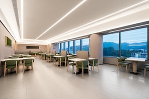 A modern, well-lit dining area with green chairs and tables, large windows offering a view of the cityscape. - Ji Hotel Guangzhou Huangpu Science City Luogang (Guangzhou)