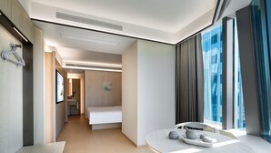 A modern hotel room with a bed, a dining table with a tray, a bench, and a view of the city through large windows. - Ji Hotel Guangzhou Huangpu Science City Luogang (Guangzhou)