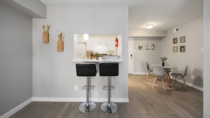 A modern kitchen with white cabinets, a central island, and two black bar stools.