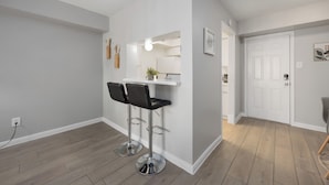A modern kitchen with white cabinets, a white countertop, and two black bar stools.
