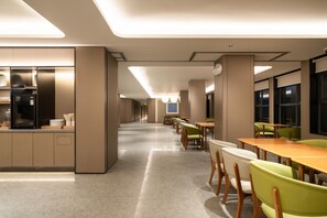 A modern dining area with a long counter, multiple tables, and chairs. - Ji Hotel Guangzhou Huadu Square Metro Station (Guangzhou)