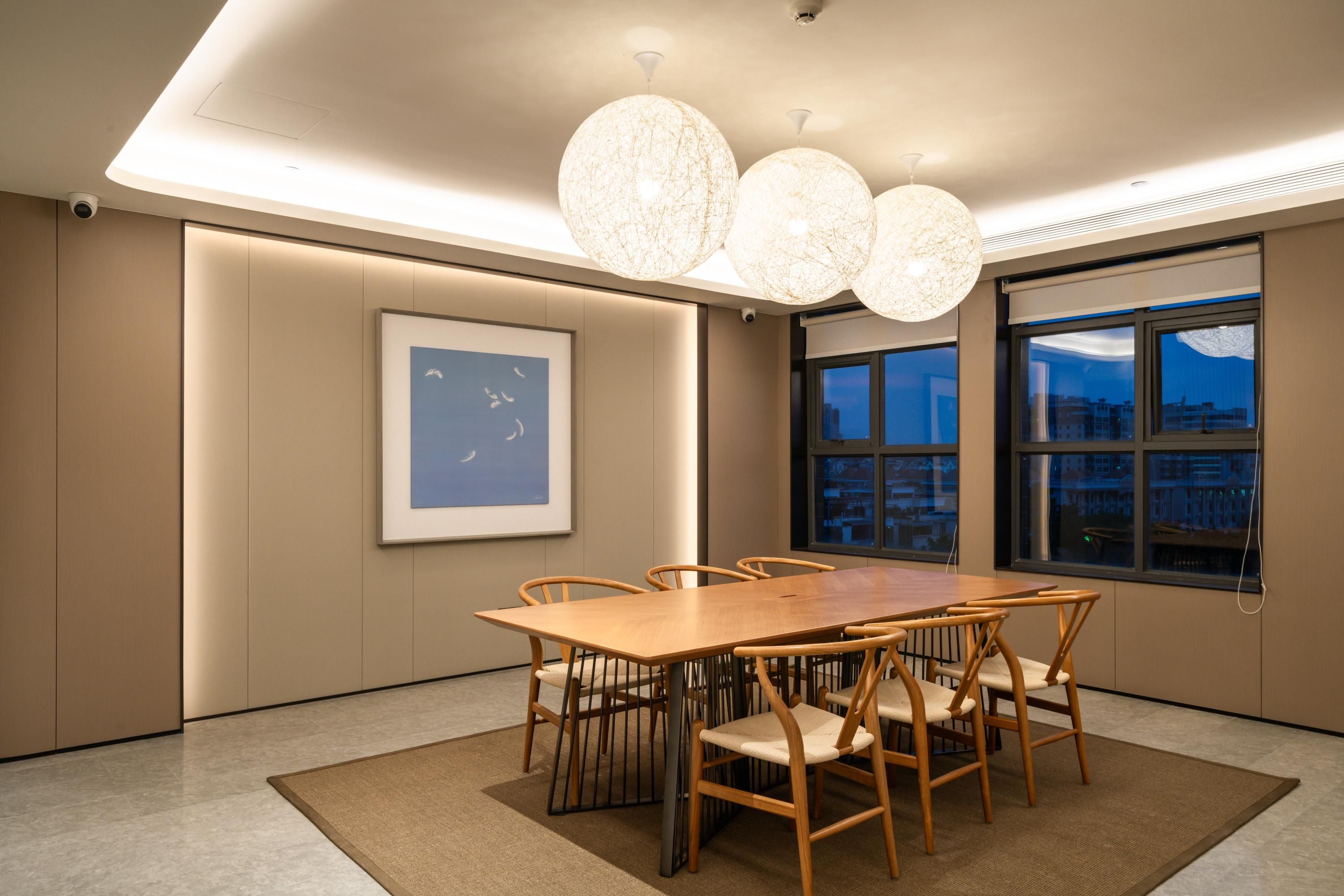 A modern conference room with a large wooden table, six chairs, and a large window with a city view.