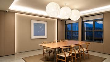 A modern conference room with a large wooden table, six chairs, and a large window with a city view.