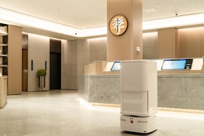 A modern hotel lobby with a reception desk, a digital kiosk, and a security camera on the ceiling. - Ji Hotel Guangzhou Huadu Square Metro Station (Guangzhou)