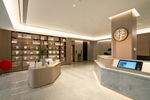 A modern reception area with a digital display, a reception desk, and a wall of framed items. - Ji Hotel Guangzhou Huadu Square Metro Station (Guangzhou)