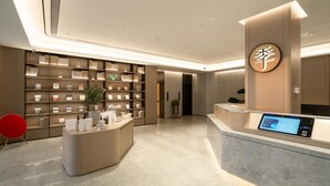 A modern reception area with a digital display, a reception desk, and a wall of framed items. - Ji Hotel Guangzhou Huadu Square Metro Station (Guangzhou)