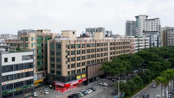 Un edificio de varios pisos con locales comerciales en la planta baja, rodeado de un estacionamiento y una calle con automóviles.