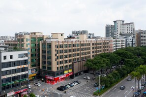 A multi-story commercial building with a ground-level retail space, surrounded by a parking lot and a street with cars. - Ji Hotel Guangzhou Huadu Square Metro Station (Guangzhou)