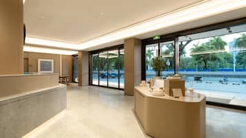 Una zona de recepción moderna con un mostrador curvo, una puerta de cristal grande que da al exterior y vistas a la calle y al follaje.