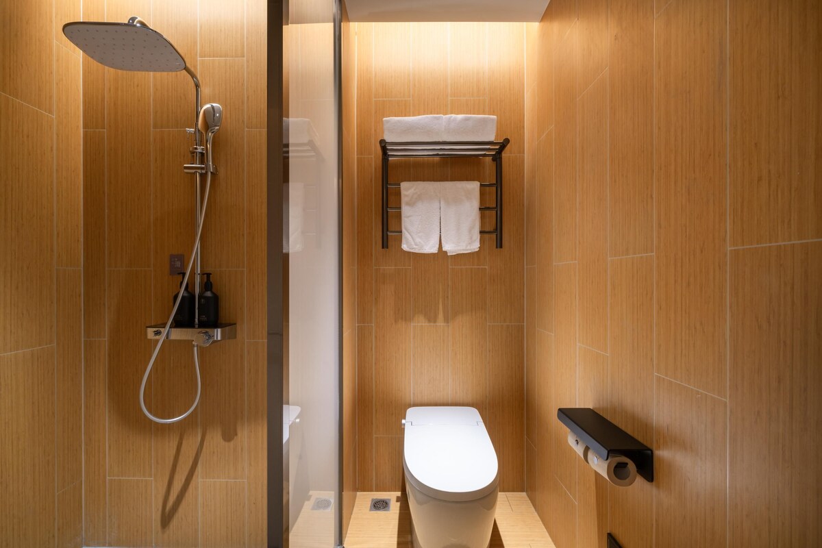 A modern bathroom with a shower, toilet, and towel rack.