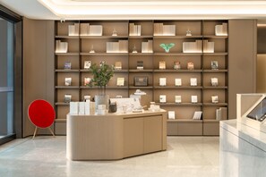 A modern reception area with a central desk, a bookshelf with awards, and a red chair. - Ji Hotel Guangzhou Huadu Square Metro Station (Guangzhou)