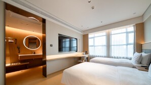 Une chambre d’hôtel avec deux lits, une télévision, un miroir, un bureau et une salle de bain avec douche et toilettes.