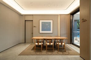 Uma sala de conferência moderna com uma mesa comprida e cadeiras, uma obra de arte emoldurada na parede e vista através de uma porta de vidro.