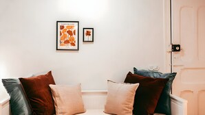 A neatly arranged bedroom with a bed, pillows, and two framed artworks on the wall.