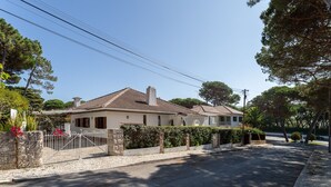 Una casa de dos pisos con techo de tejas, paredes de piedra y entrada pavimentada.