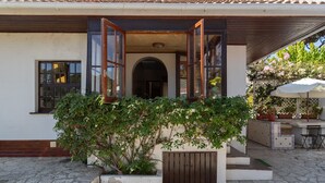Una casa con techo de tejas, puerta de madera y un pequeño jardín con un banco y plantas en macetas.