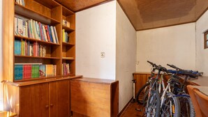 Una habitación con estanterías de madera llenas de libros, un escritorio de madera y bicicletas apoyadas en la pared.