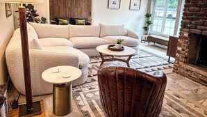 A modern living room with a sectional sofa, a round coffee table, a floor lamp, and a brick fireplace.