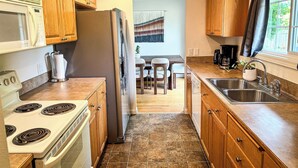 A kitchen with wooden cabinets, a stove, a refrigerator, and a dining area with a table and chairs.